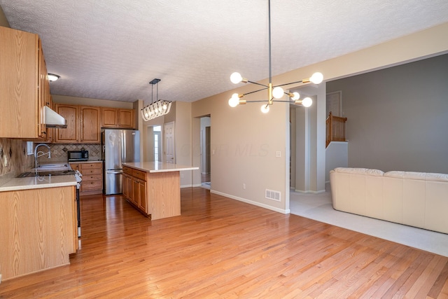 kitchen with visible vents, open floor plan, a center island, freestanding refrigerator, and under cabinet range hood