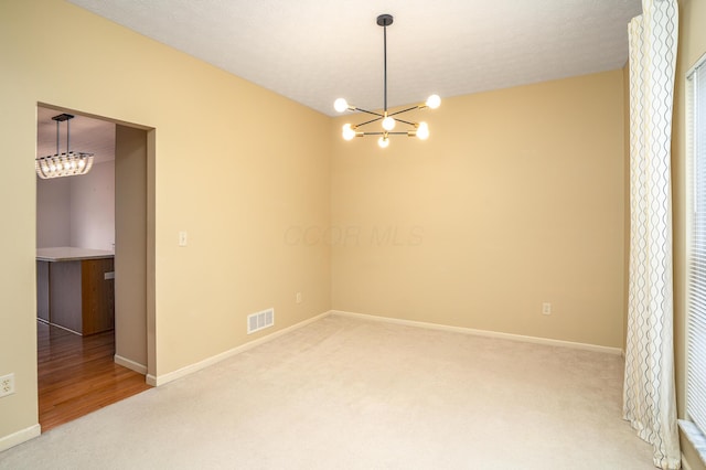 unfurnished room with baseboards, visible vents, a notable chandelier, and light colored carpet