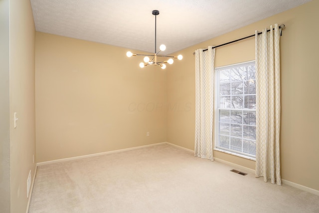 empty room with a textured ceiling, light colored carpet, visible vents, baseboards, and an inviting chandelier