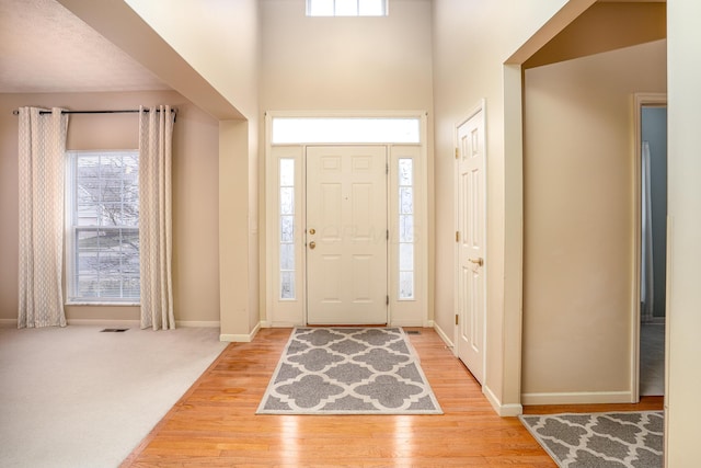 foyer entrance featuring baseboards, visible vents, and wood finished floors