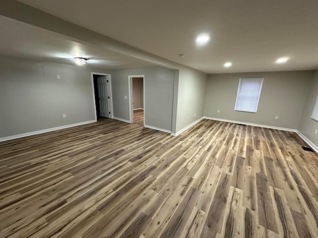 below grade area featuring recessed lighting, dark wood-style flooring, visible vents, and baseboards