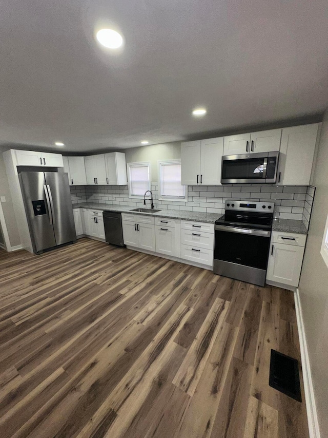 kitchen with appliances with stainless steel finishes, dark wood-type flooring, a sink, and visible vents