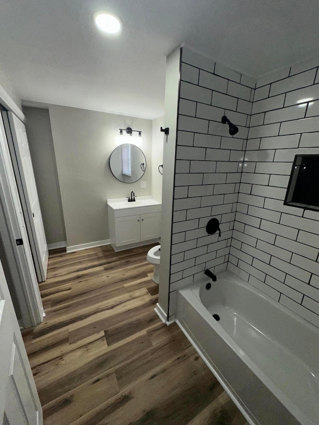 full bath with shower / bathtub combination, toilet, wood finished floors, vanity, and baseboards