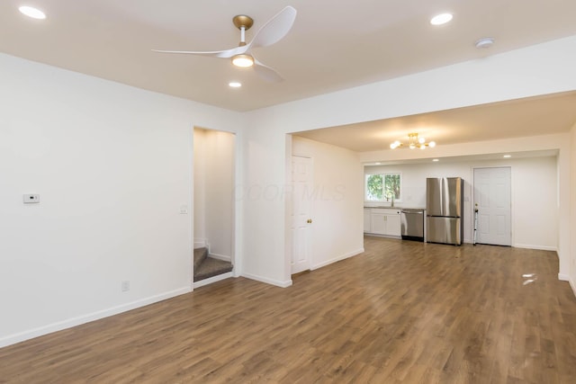 unfurnished living room with wood finished floors, baseboards, recessed lighting, a sink, and ceiling fan with notable chandelier