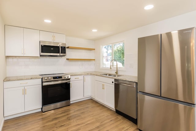 kitchen featuring light wood-style flooring, a sink, open shelves, appliances with stainless steel finishes, and white cabinets