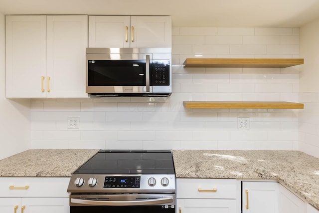 kitchen with backsplash, light stone countertops, white cabinets, stainless steel appliances, and open shelves