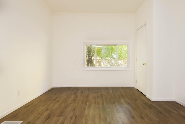 empty room with crown molding, wood finished floors, and baseboards