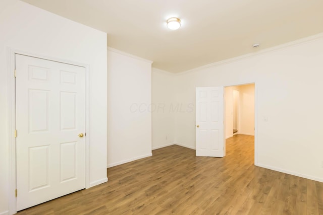 unfurnished bedroom featuring baseboards, light wood finished floors, and ornamental molding