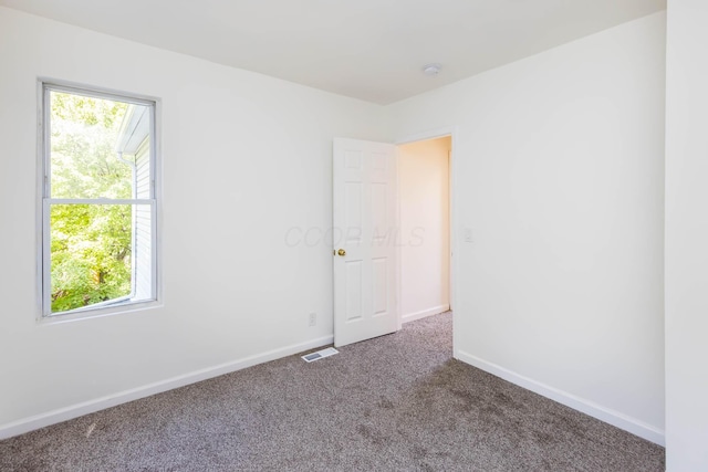 carpeted empty room featuring visible vents and baseboards