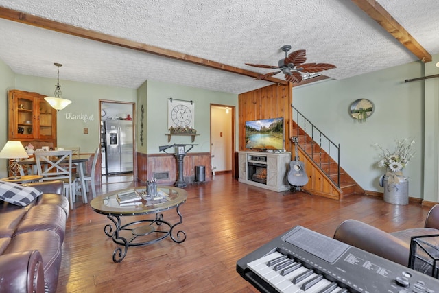 living area with stairs, wood finished floors, and beam ceiling