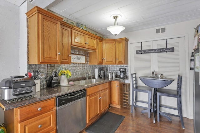 kitchen featuring dishwasher, backsplash, a sink, and visible vents