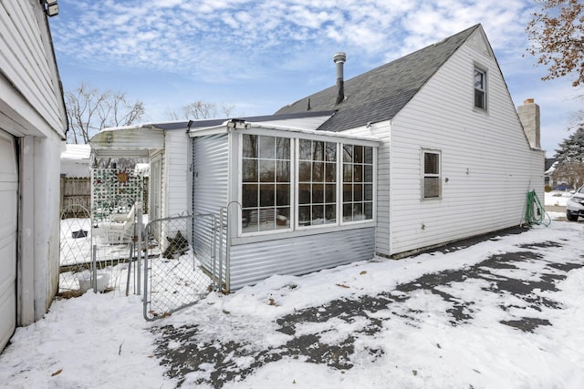 snow covered house with roof with shingles and fence