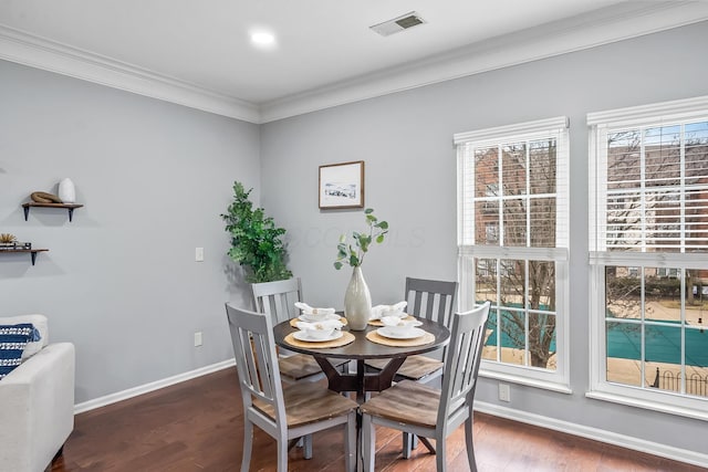 dining area featuring baseboards, visible vents, wood finished floors, and ornamental molding