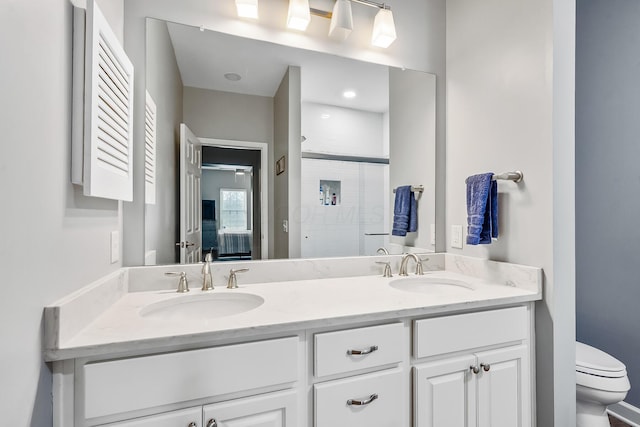 bathroom featuring a stall shower, a sink, toilet, and double vanity