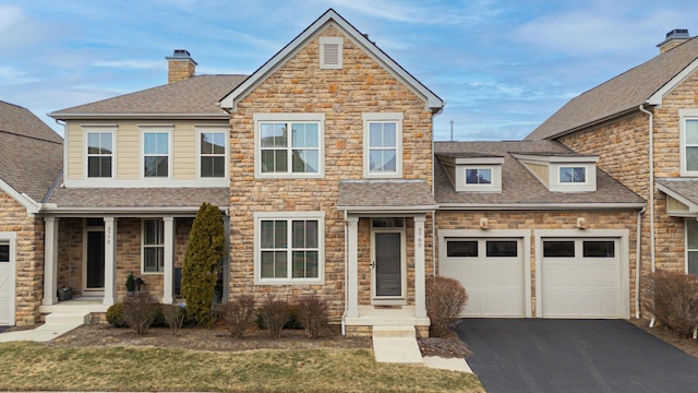 view of front of home with driveway, a chimney, roof with shingles, an attached garage, and a front yard