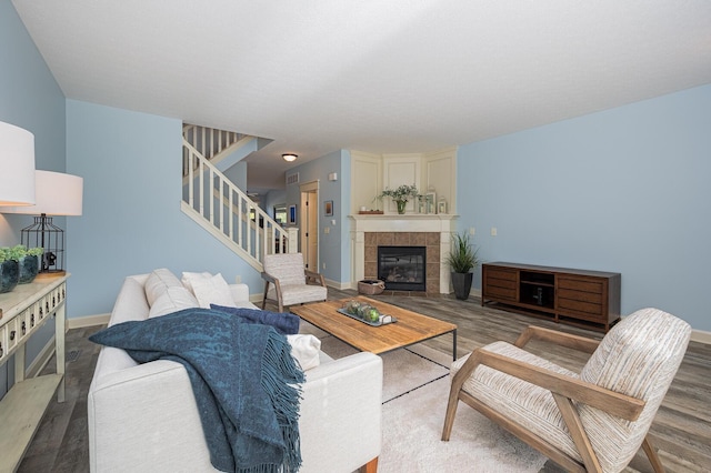 living area featuring baseboards, a fireplace, stairway, and wood finished floors