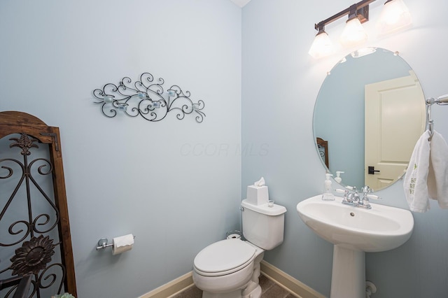 bathroom with baseboards, a sink, and toilet