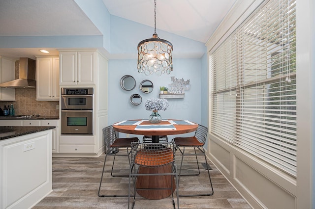 dining space featuring lofted ceiling, a notable chandelier, and wood finished floors