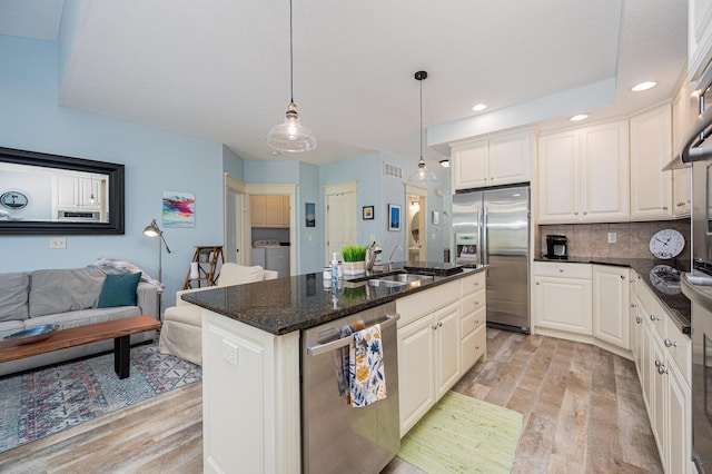 kitchen featuring light wood-style flooring, stainless steel appliances, a sink, and washing machine and clothes dryer