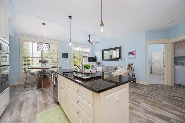 kitchen featuring washer / dryer, plenty of natural light, a sink, and light wood finished floors