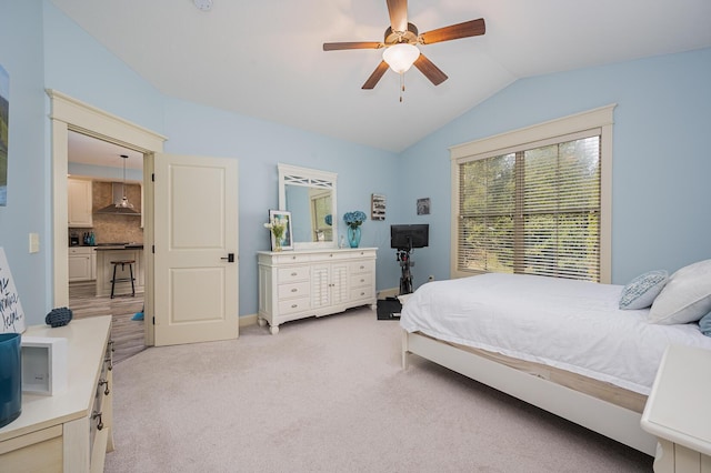 bedroom featuring a ceiling fan, light carpet, vaulted ceiling, and baseboards