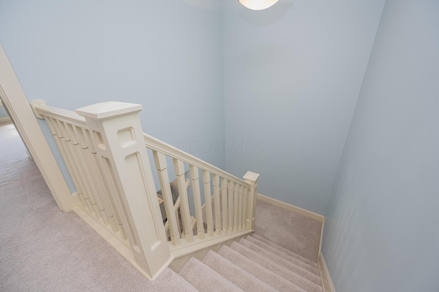 staircase featuring baseboards and carpet flooring