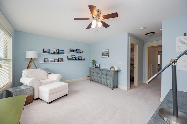 living area with carpet, baseboards, and a ceiling fan