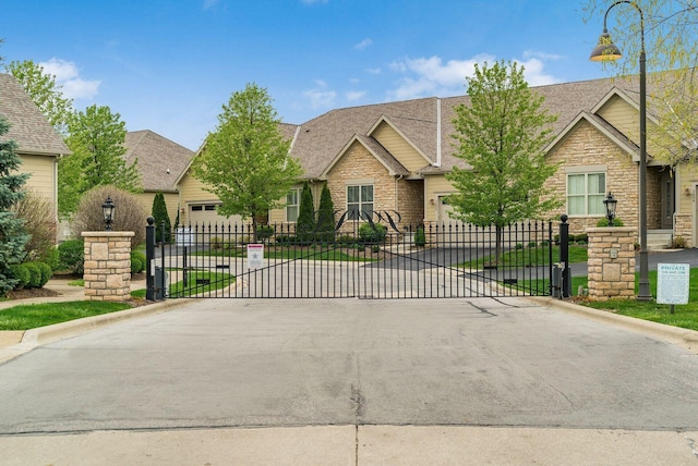 view of front of home with concrete driveway, stone siding, and a gate