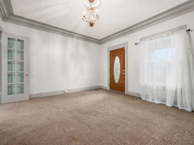 foyer with a textured ceiling, carpet floors, ornamental molding, and a notable chandelier