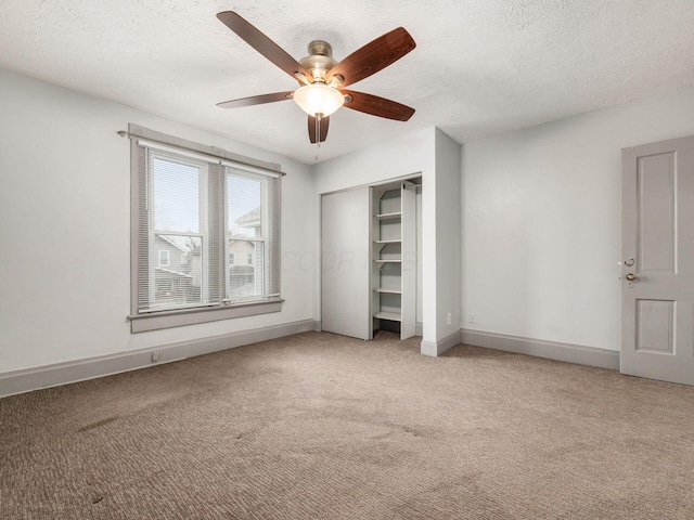 unfurnished bedroom featuring light carpet, a closet, a textured ceiling, and baseboards