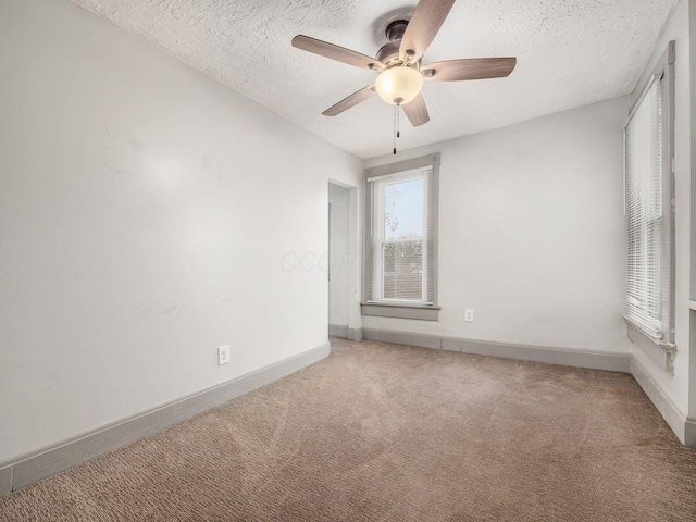 carpeted empty room featuring a ceiling fan, baseboards, and a textured ceiling