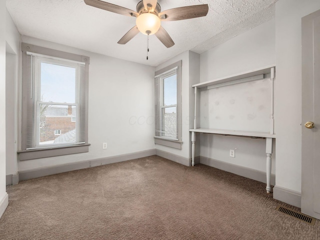 unfurnished bedroom with carpet, a textured ceiling, and baseboards