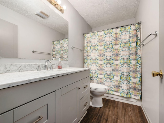 full bath with toilet, a textured ceiling, wood finished floors, and vanity