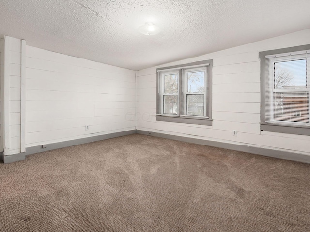 empty room featuring carpet flooring, a textured ceiling, and baseboards