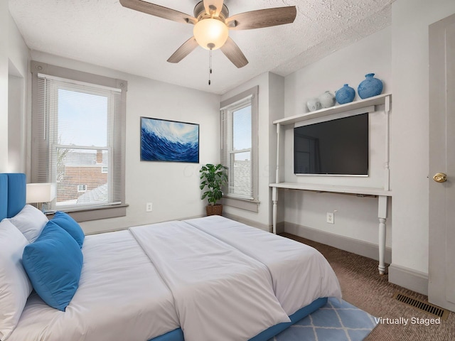 bedroom featuring a textured ceiling, ceiling fan, visible vents, baseboards, and carpet