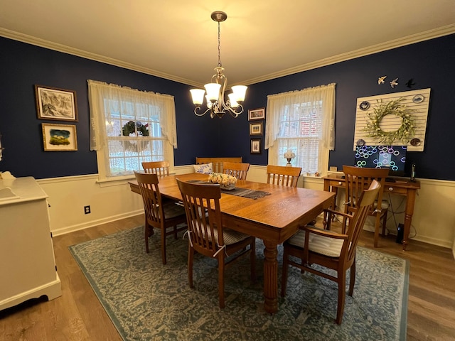 dining room featuring wainscoting, ornamental molding, an inviting chandelier, and wood finished floors