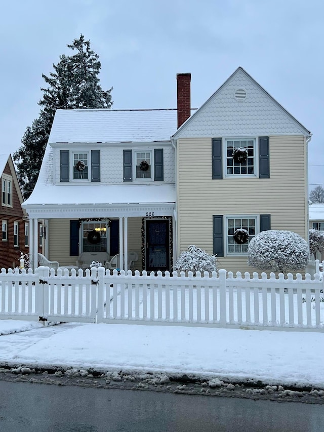 view of front of home featuring a fenced front yard, a porch, and a chimney