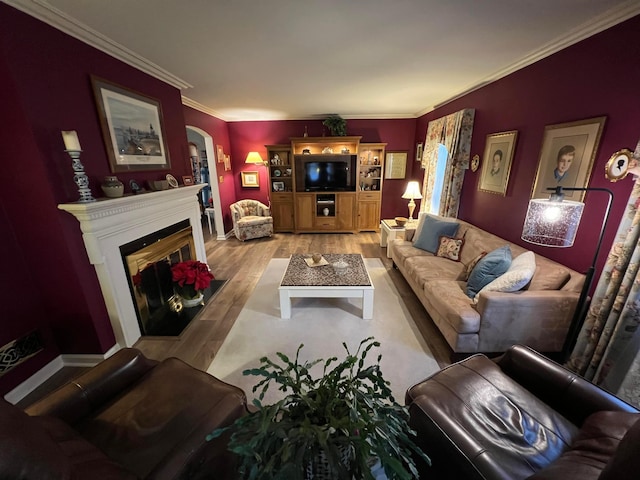 living area featuring arched walkways, a fireplace with flush hearth, crown molding, and light wood-style floors