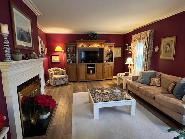 living area with a glass covered fireplace, ornamental molding, and light wood finished floors