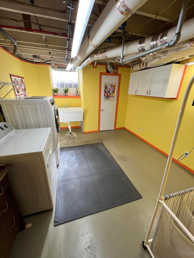 below grade area featuring a sink, baseboards, and washer and clothes dryer