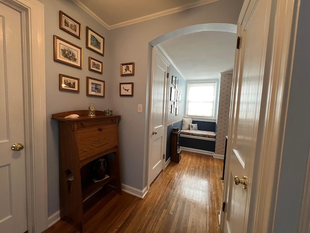 corridor featuring baseboards, wood finished floors, arched walkways, and ornamental molding