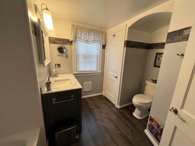 bathroom with vanity, wood finished floors, visible vents, baseboards, and toilet