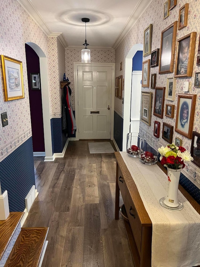 corridor featuring arched walkways, dark wood-style floors, wallpapered walls, and crown molding