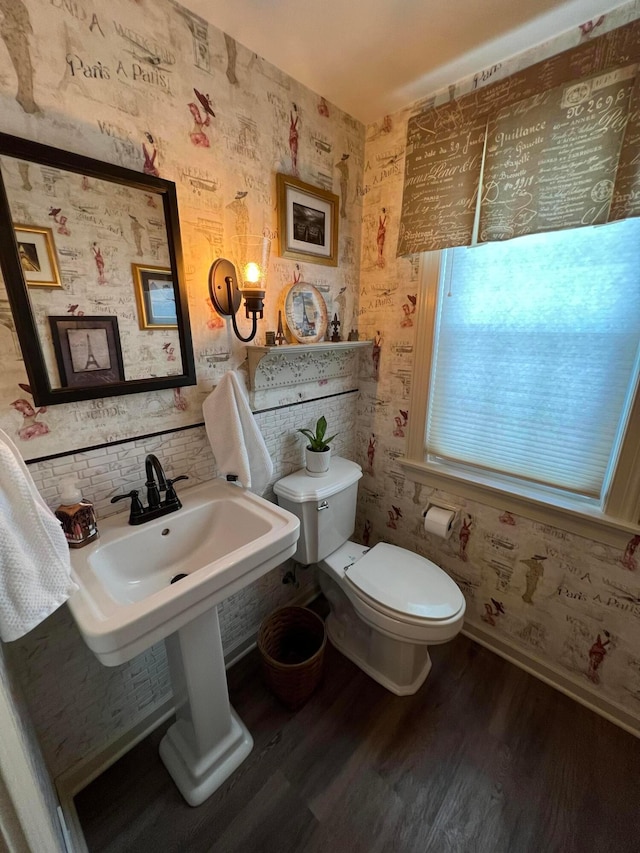 bathroom with toilet, wallpapered walls, baseboards, and wood finished floors