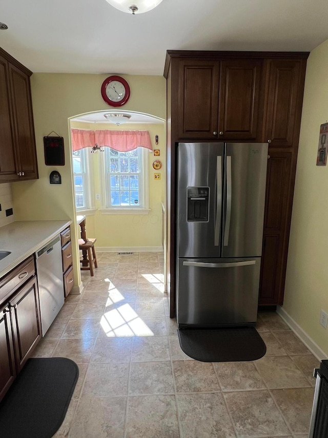 kitchen featuring dark brown cabinets, appliances with stainless steel finishes, light countertops, and baseboards