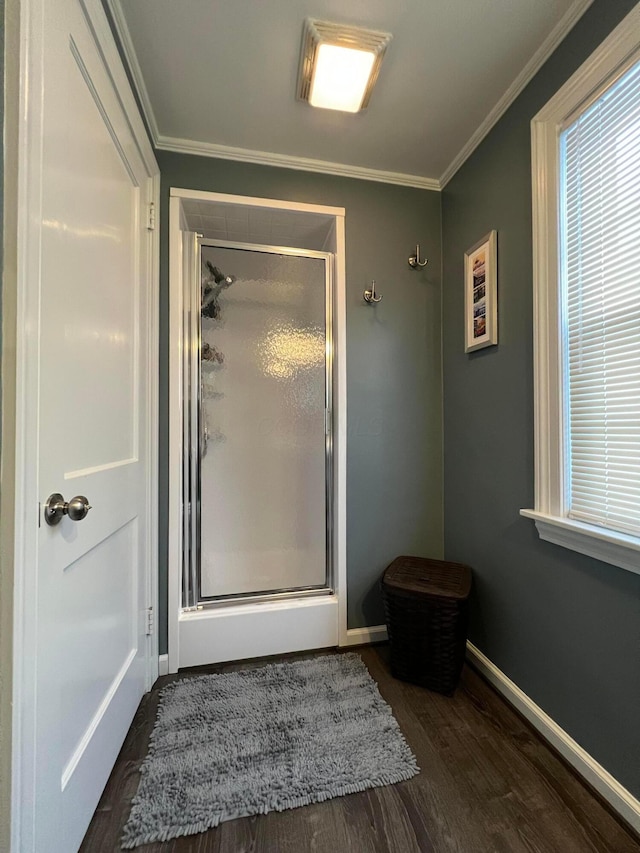 full bath with crown molding, wood finished floors, a stall shower, and baseboards