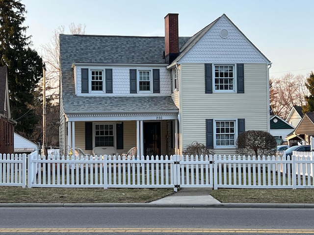 view of front of home with a fenced front yard, a porch, a chimney, and roof with shingles