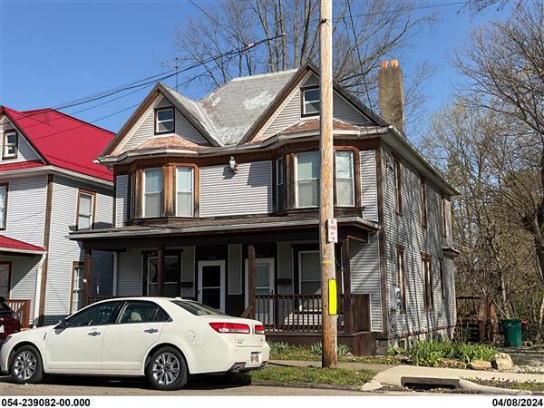 view of front facade featuring covered porch and a chimney