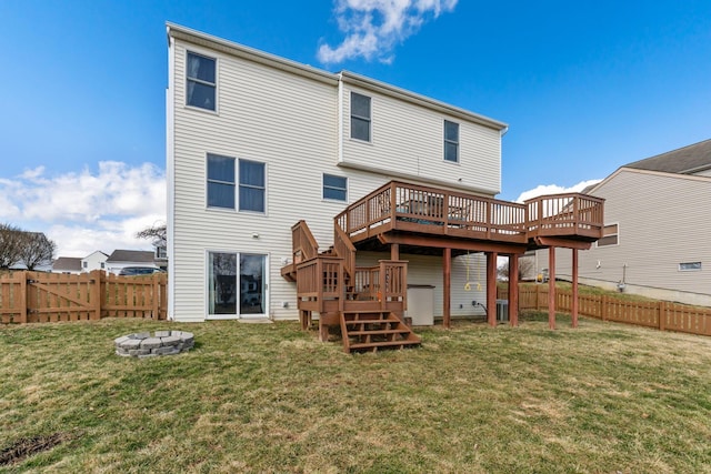 rear view of property with a fire pit, a deck, a lawn, and a fenced backyard