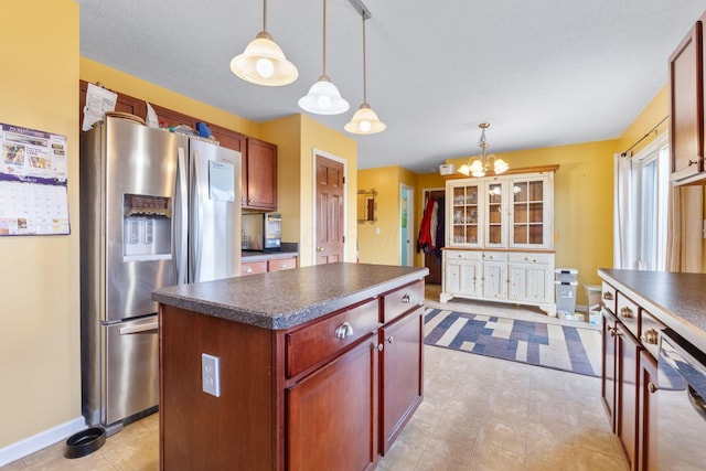 kitchen featuring appliances with stainless steel finishes, a center island, reddish brown cabinets, dark countertops, and pendant lighting